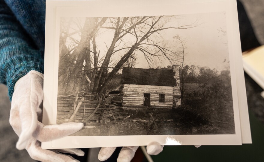 Renata Lisowski, director of the Archive and Research Center at the Chevy Chase Historical Society, holds a photo of a cabin that once sat near the neighborhood of the Rollingwood Burial Ground.