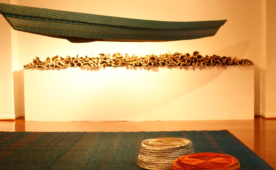 A traditional canoe covered with intricate beaded designs hangs in the gallery. This piece was created by artisans in a workshop founded by Jorge Lizarazo.