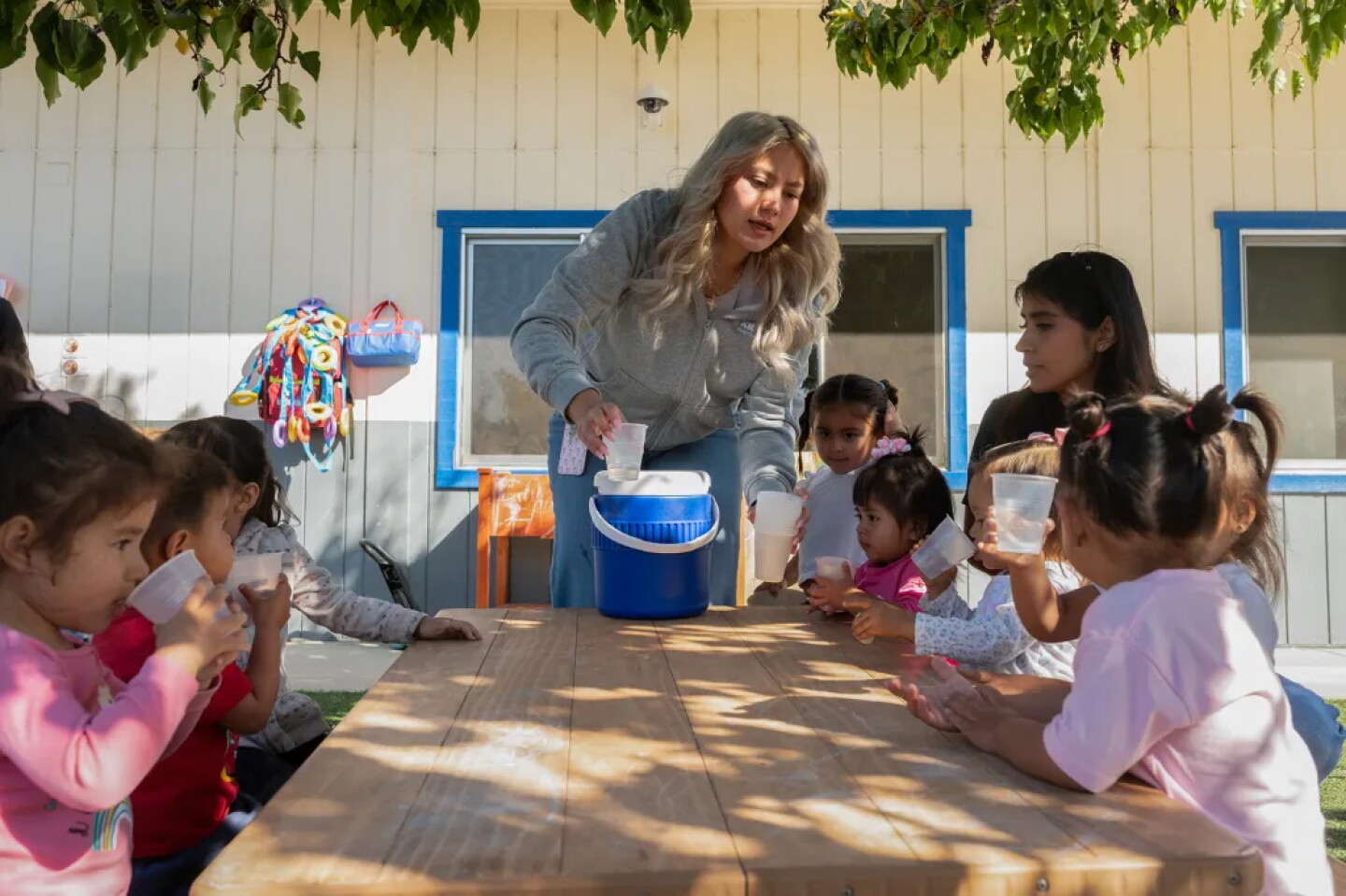 Childcare workers distribute glasses of water during recess.