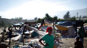 A woman stands near a makeshift refugee camp near downtown Port-au-Prince on Jan. 16. The government is now planning to relocate many survivors to formal camps on the outskirts of town.