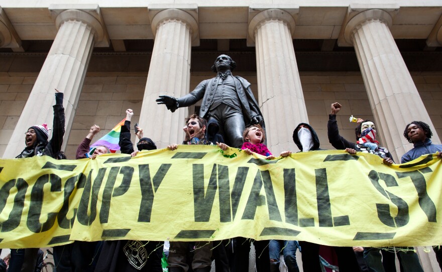 Occupy Wall Street demonstrators stand and cheer in front of the George Washington statue on Wall Street. Millennials were heavily involved in this movement.