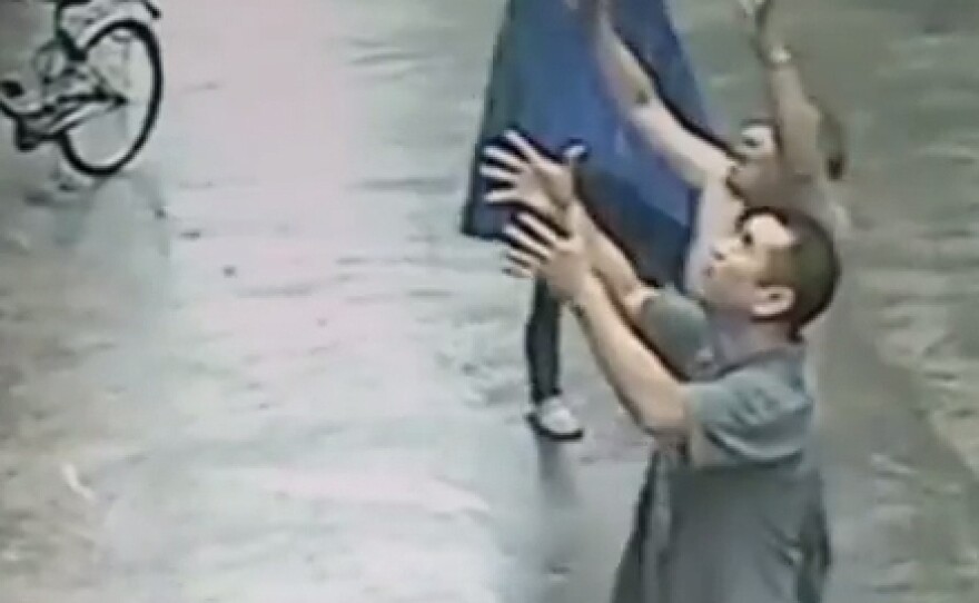 Men watch as a baby teeters on an ledge in China earlier this week. The infant fell — and was safely caught, making his saviors into heroes in Chinese social media.