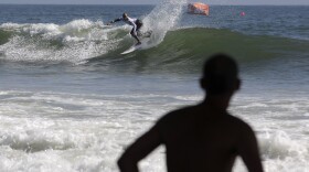 A man watches as Kelly Slater competes in the U.S. Open of Surfing event in Huntington Beach, Calif., Thursday, Aug. 4, 2011.