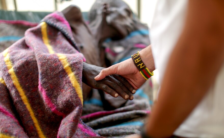 The kids in the camp made a beaded bracelet for Dr. Nav, who clasps the hand of a patient in the tuberculosis ward.