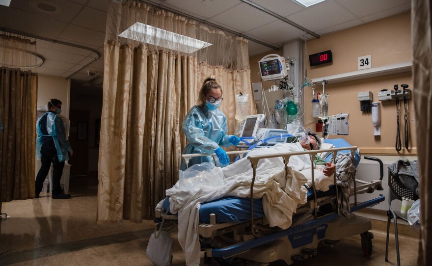 A health care worker tends to a COVID-19 patient who is using a continuous positive airway pressure machine to aid her breathing at Providence St. Mary Medical Center in Apple Valley, Calif., in January 2021.