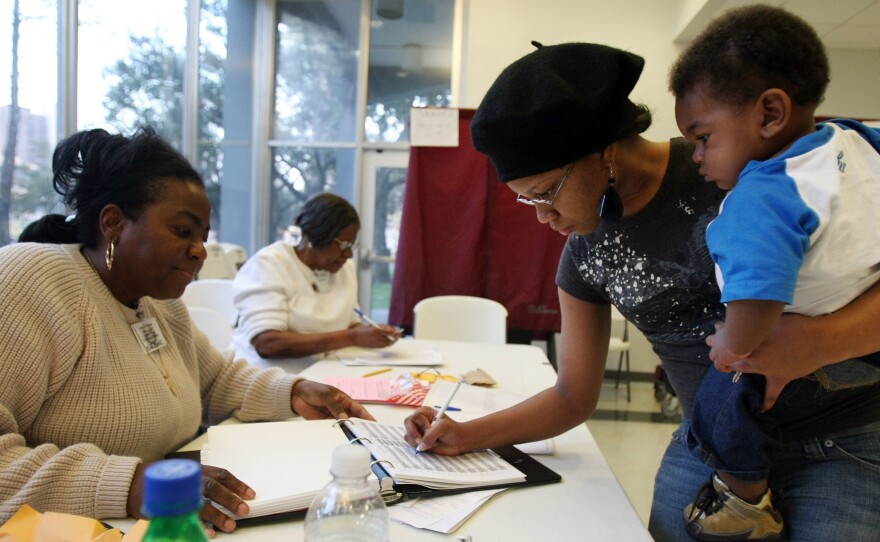 Charnisha Thomas signs in during the Louisiana presidential primary in 2008. In a new poll released Monday, African-American voters say they wait in longer lines and travel farther to get to polling places than white voters.