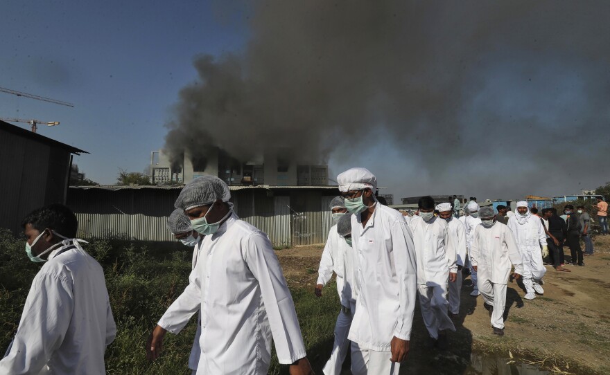 Employees leave as smoke rises from an electrical fire at Serum Institute of India on Jan. 21. Five deaths occurred as a result of the fire, but vaccine production was not hampered.