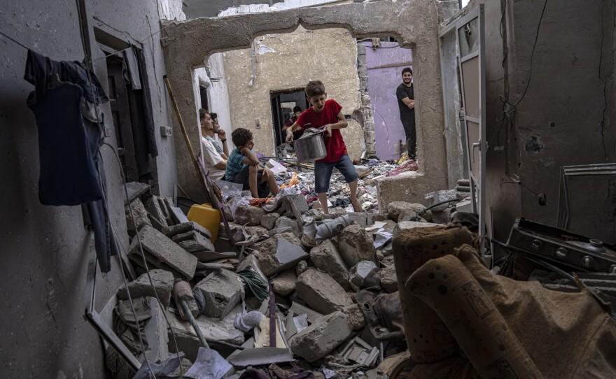 Palestinians inspect the rubble of a house after it was struck by an Israeli airstrike in Khan Younis, southern Gaza Strip, Sunday, Oct. 29, 2023.