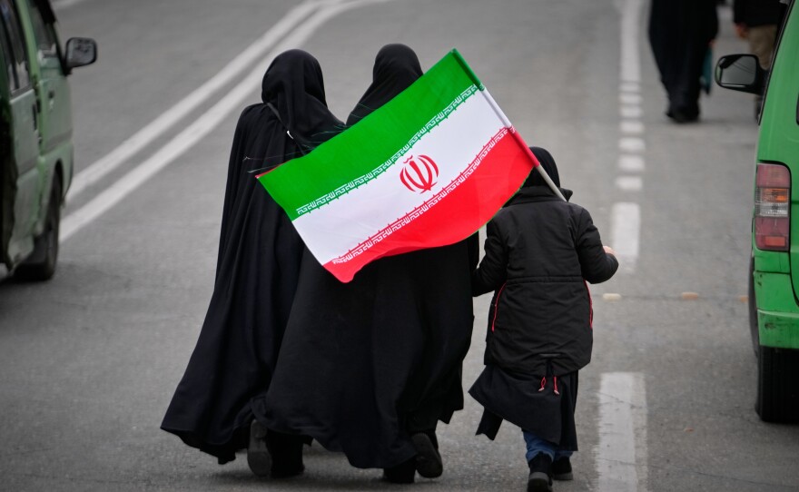Two women and a child holding an Iranian flag walk toward the Imam Khomeini Grand Mosque to attend Friday prayers in Tehran, Iran, on Friday.