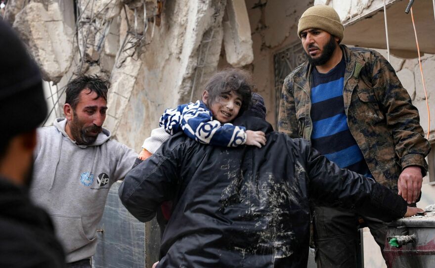 Residents retrieve a small child from the rubble of a collapsed building following an earthquake in the town of Jandaris, in the countryside of Syria's northwestern city of Afrin, on Monday.