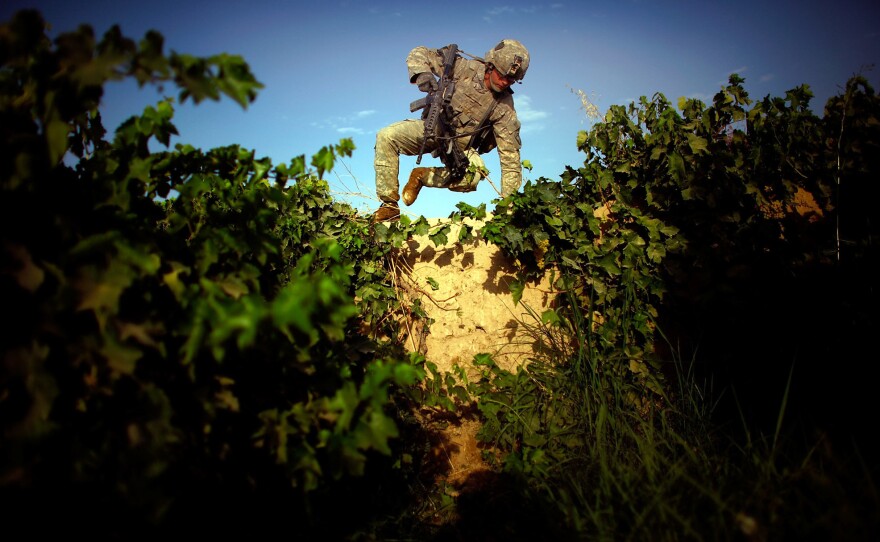 Pfc. James Turner with Bravo Company, 101st Airborne Division jumps over an 8-foot-high mud wall while navigating a grape field and trying to avoid walking on a heavily traveled path in the Pashmul District of Kandahar province in southern Afghanistan.