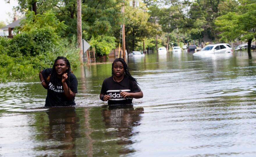 People wade along a flooded street in Bay Shore. The area is next to the town of Islip, which saw the heaviest rain.