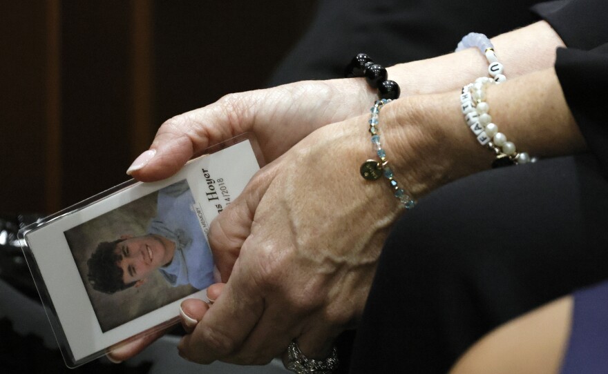 Gena Hoyer holds a photograph of her son, Luke, who was killed in the 2018 shootings, as she awaits the verdict at the Broward County Courthouse on Thursday.