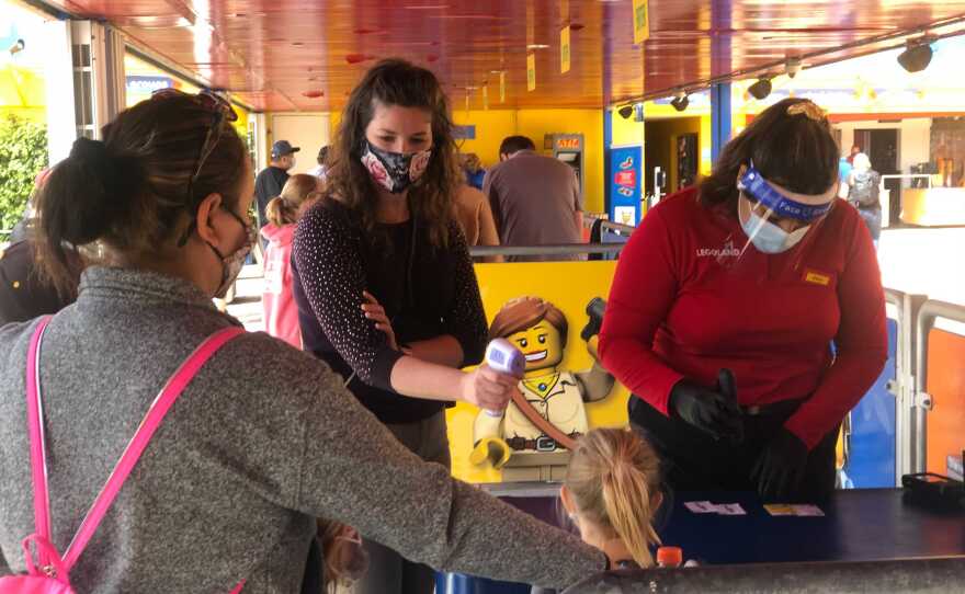 A child has their temperature taken at the entrance of Legoland, April 15, 2021.