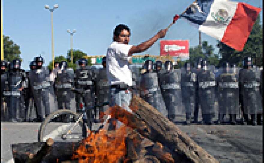 A member of the Oaxaca People's Popular Assembly waves a national flag during a street blockade in Oaxaca on Oct. 29, 2006.