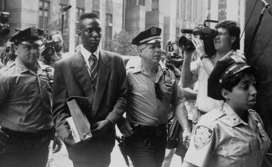 Yusef Salaam walks into court flanked by police and press.