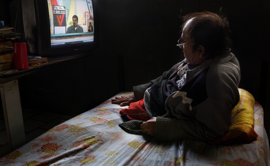 A resident at the senior home watches a news report featuring Venezuelan president Nicolas Maduro.