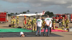 A JSX plane on the runway in the background as emergency crews conduct a disaster drill at McClellan-Palomar Airport, Oct. 23, 2025.