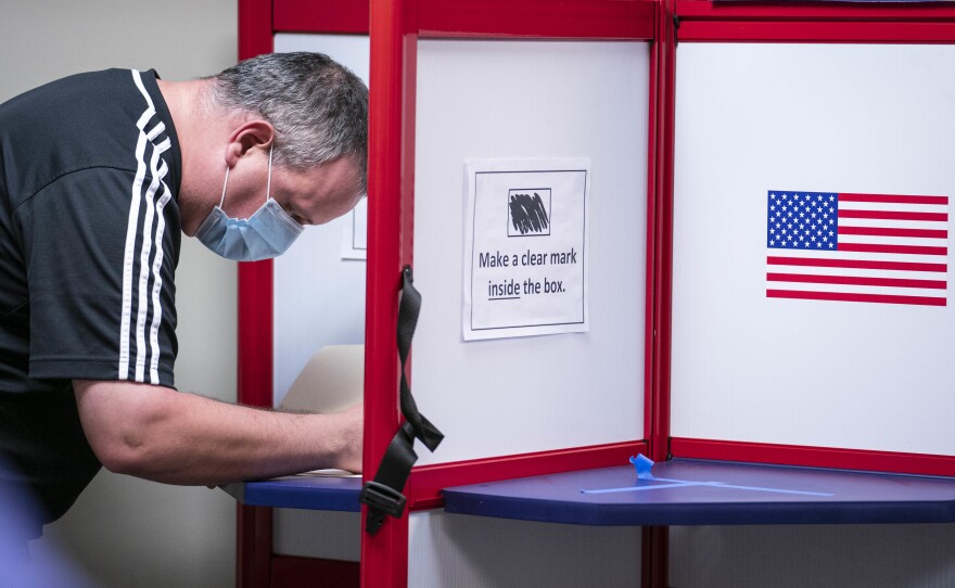 A man casts his ballot for the 2020 presidential election at an early voting location in Alexandria, Va. Voters in Virginia will now be able to register until 11:59 p.m. on Thursday, in person or online.