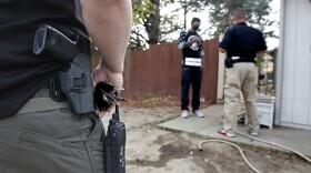 Parole agent Andy Correa,left, stands watch as parole agent Clint Cooley, right, talks with a sex-offender parolee during a stop in Sacramento, Dec. 1, 2015. 