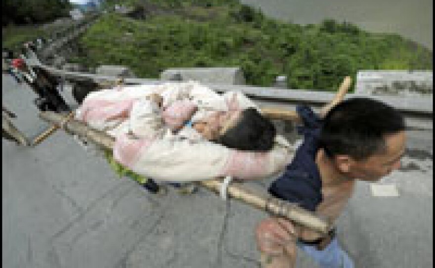 An injured woman is carried along a partially collapsed road in mountainous Wenchuan county, in western China.