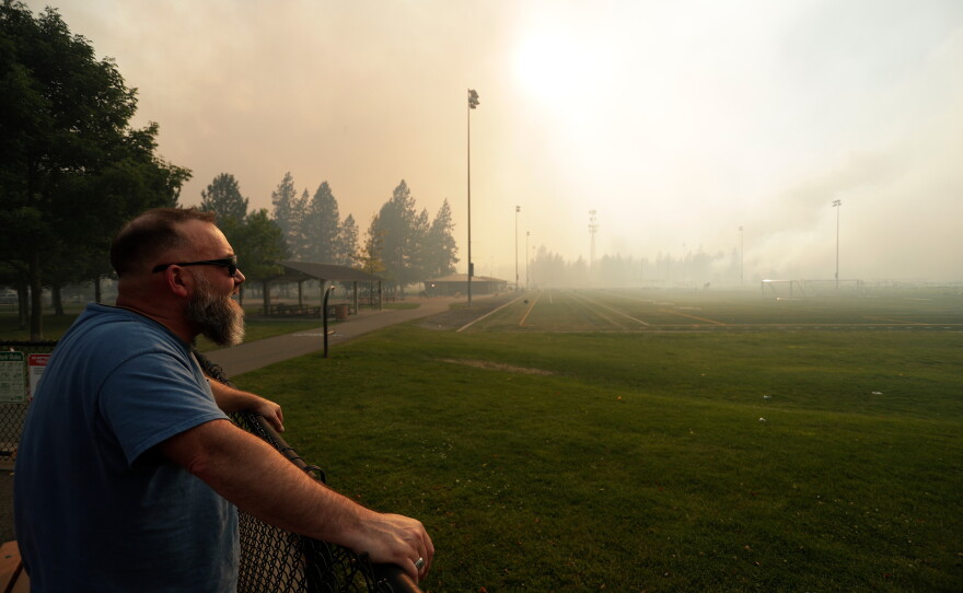 Andrew Rowley watches Old Trails Fire from Dwight Merkel Sports Complex after evacuating, on Aug. 1, 2026, in Spokane, Wash.