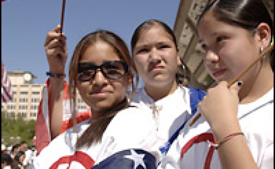 Middle school students Maria Mancera, Cindy Roque and Magaly Mancera hold U.S. flags as they watch protesters at the Mega March on City Hall in Dallas on Sunday.
