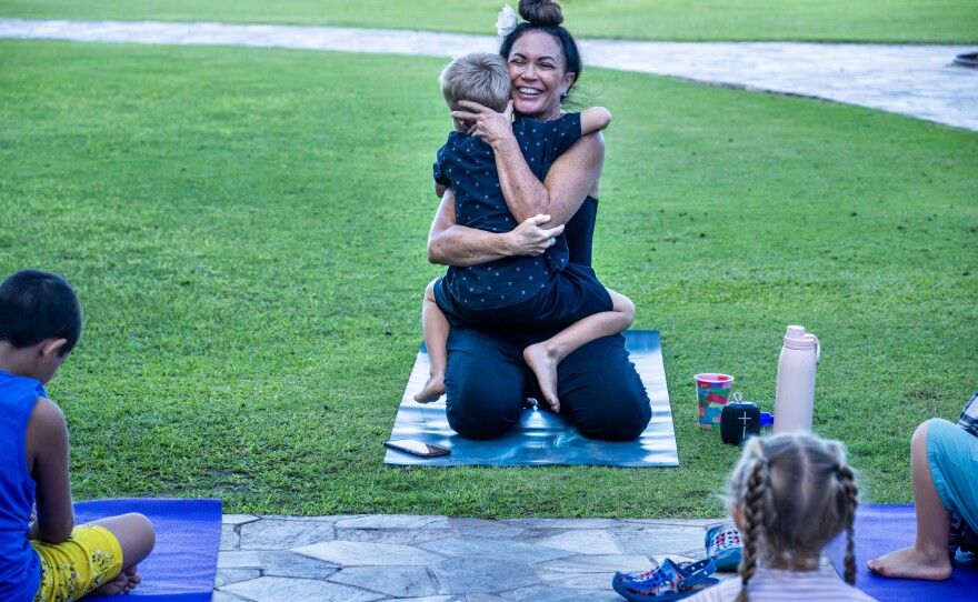 Kilihune Ka'aihue gets a hug from a child after she teaches a yoga class to displaced children from Lahaina, many who lost their homes.