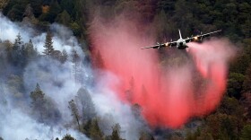A federal firefighting plane drops a load of fire retardant over a smoldering hillside in Middletown, California,  Sept. 15, 2015.