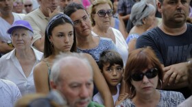 People observe a minute of silence in memory of the terror attack victims in Cambrils, Spain, Friday, Aug. 18, 2017.