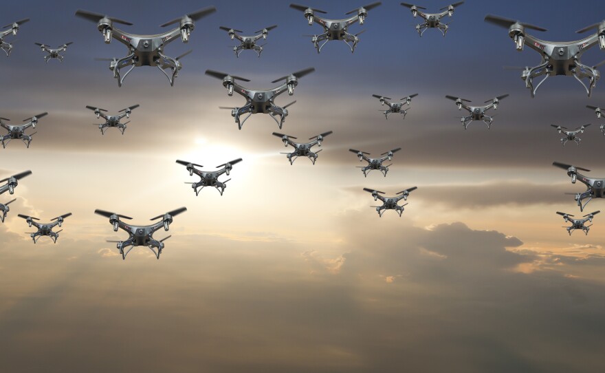 A flock of drones flying against a sunset. On Wednesday the Department of Transportation announced the launch of a pilot program that will lead to new regulations.