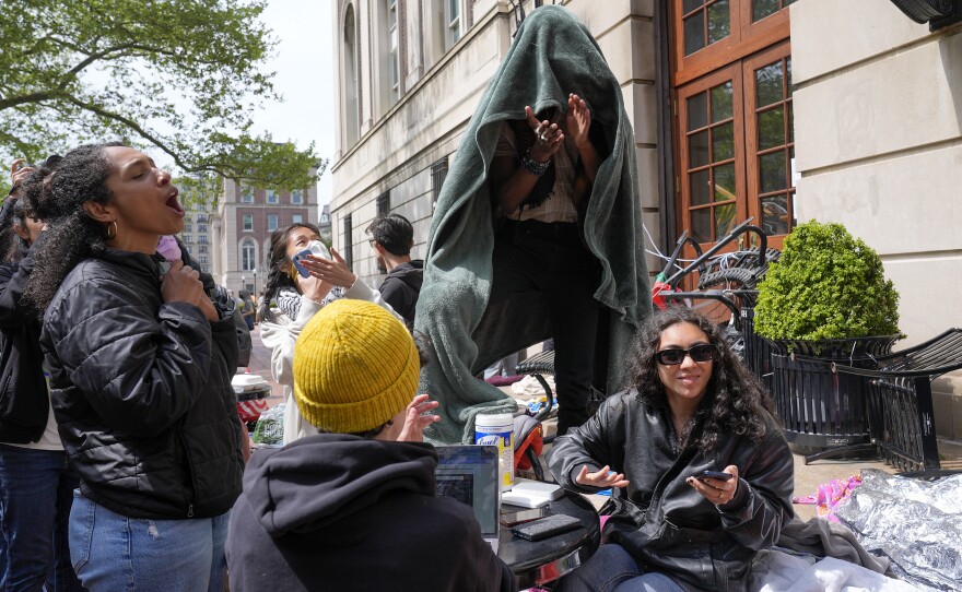 Student protesters react to the news that Brown University has agreed to hear a divestment proposal as they camp near the entrance to Hamilton Hall on the campus of Columbia University, Tuesday, in New York.