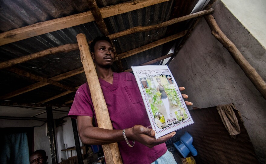 Sule Koroma displays a photo of his sister taken days before she died of Ebola.