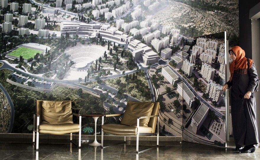 A Rawabi visitor exits the bathroom, which blends in with the photo of the new town.