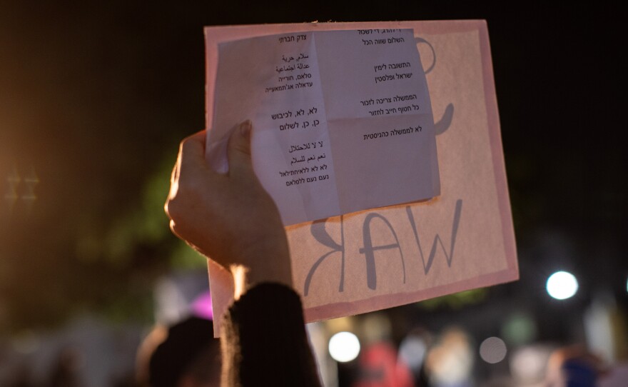 A woman holds a list of chants written in Hebrew and Arabic during the rally.