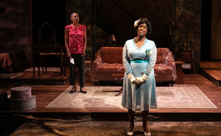 An actor watches while another is in the spotlight, in front of the stage at the Cygnet Theater