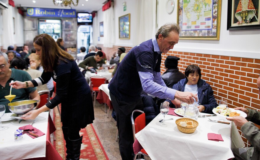 Volunteers serve free dinner to homeless people at Robin Hood restaurant in Madrid.