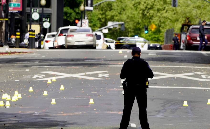 A Sacramento city police officer stands near a field of evidence markers after a mass shooting that left six people dead over the weekend.