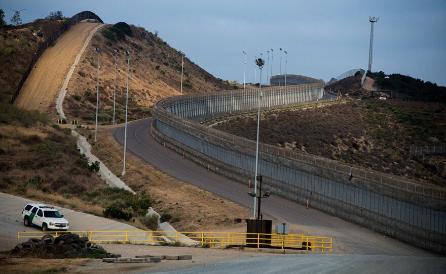 Two layers of fencing, one covered in concertina wire, follow a road near the San Ysidro Port of Entry in San Diego on Aug. 16, 2017. 