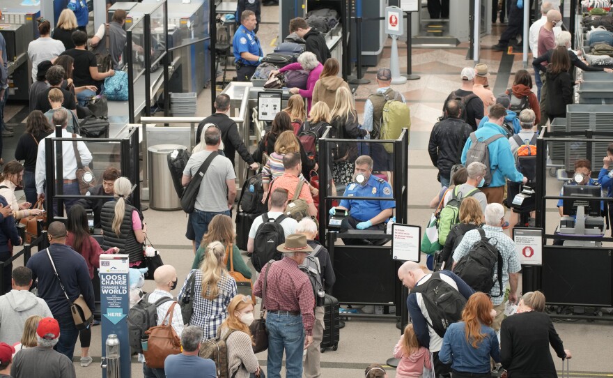 Travelers queue up as they move through the north security checkpoint in the main terminal of Denver International Airport, Thursday, May 26, 2022.
