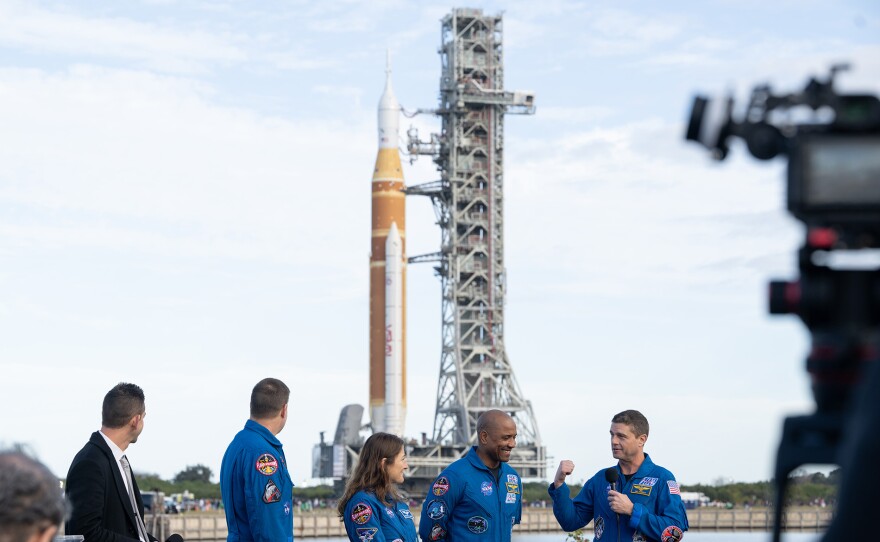 NASA astronaut Reid Wiseman, Artemis II commander, right, speaks to members of the media alongside NASA Administrator Jared Isaacman, left, CSA (Canadian Space Agency) astronaut Jeremy Hansen, Artemis II mission specialist, NASA astronaut Christina Koch, Artemis II mission specialist, and NASA astronaut Victor Glover, Artemis II pilot, as NASA’s Artemis II SLS (Space Launch System) rocket and Orion spacecraft rolls out to Launch Complex 39B at NASA’s Kennedy Space Center in Florida on Saturday, Jan. 17, 2026. In the coming weeks, engineers will prepare for the wet dress rehearsal, a two-day test that simulates launch day. The Artemis II test flight will take Commander Reid Wiseman, Pilot Victor Glover, and Mission Specialist Christina Koch from NASA, and Mission Specialist Jeremy Hansen from the CSA (Canadian Space Agency), around the Moon and back to Earth no later than April 2026. Photo Credit: (NASA/Joel Kowsky)