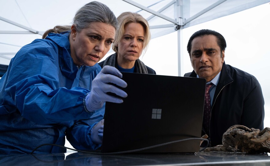 Shown L-R: Dr. Leanne Balcombe (Georgia Mackenzie), DCI Jess James (Sinéad Keenan), DI Sunny Khan (Sanjeev Bhaskar). UNFORGOTTEN Season 6 MASTERPIECE  Episode 1. When a spine is dredged out of Whitney Marsh, a new case begins for the team. Both Jess and Sunny are glad of a new challenge, given their strained personal lives.    