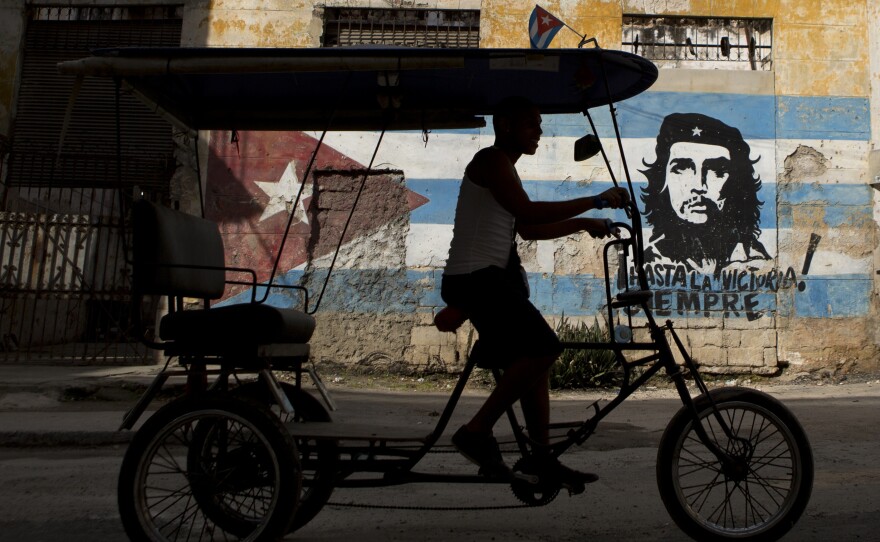 A bicycle taxi rides past a building painted with a Cuban flag and an image of Che Guevara, along with the Spanish slogan, "Always toward victory!" ahead of President Obama's visit in Havana on March 19.
