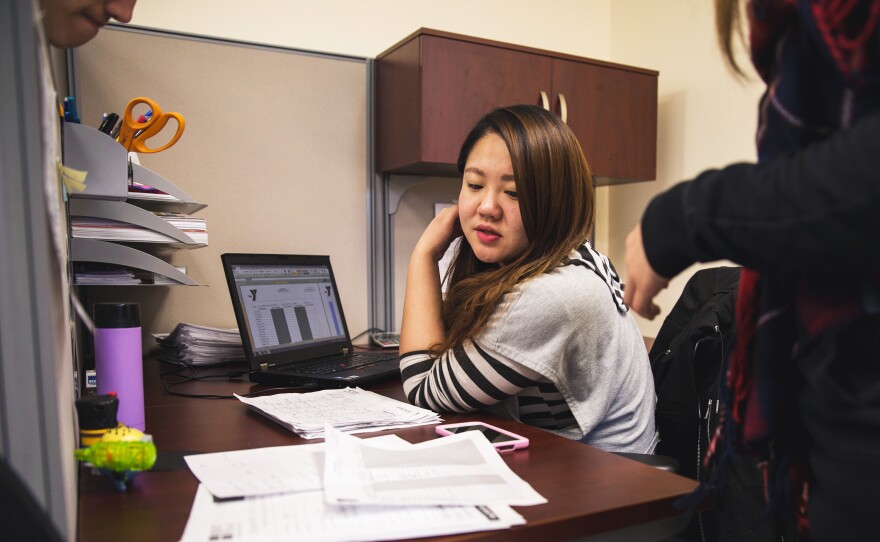 Sabrina Zhang, an administrative assistant at the Flushing YMCA's New Americans Welcome Center, looks over documents with her co-workers. Zhang emigrated from Liaoning province in northeast China and now works closely with immigrants in the community as they settle into life in the United States.