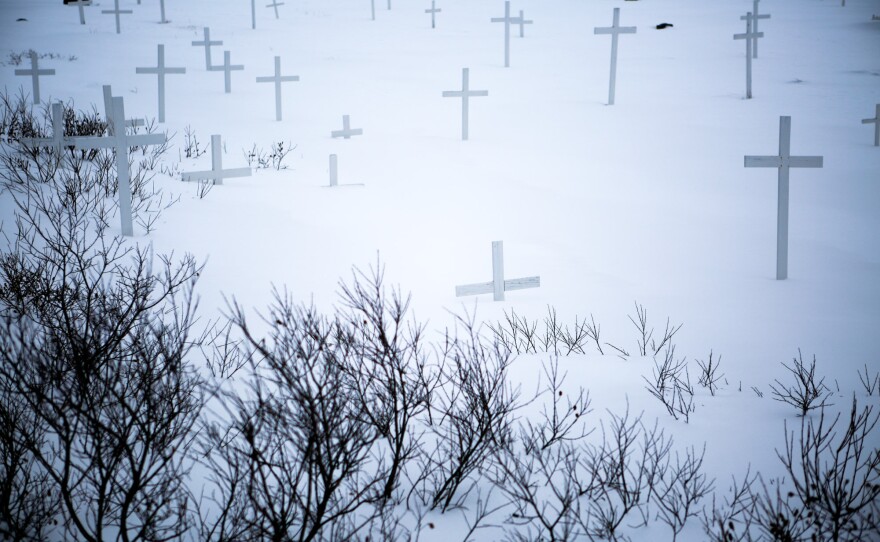 Grave markers and barren shrubs buried by snow in a Nuuk cemetery.