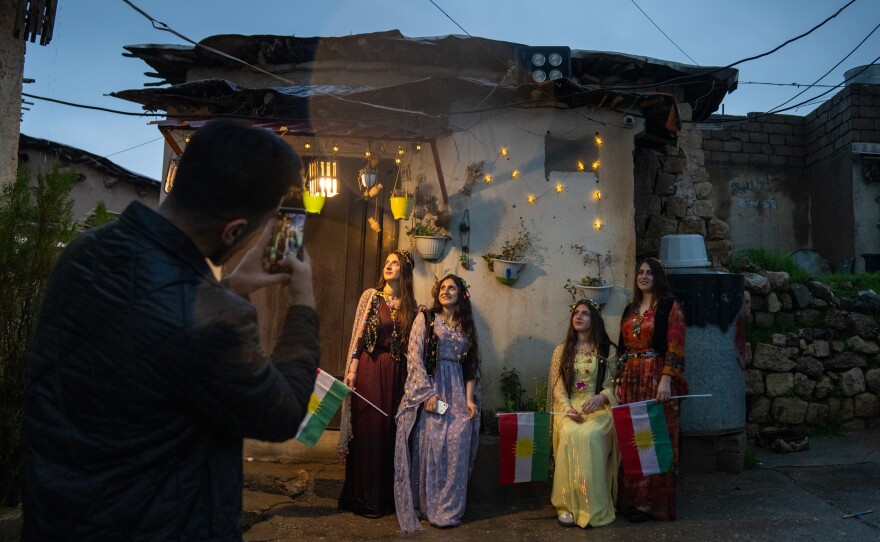 Women pose for photos dressed in traditional Kurdish clothing.