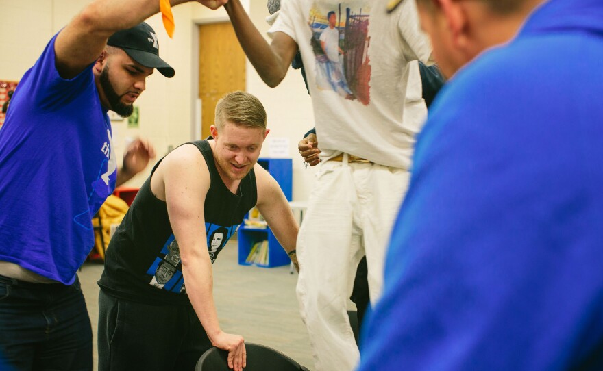 (From left) Marine veterans Richard Rivera and Dasovich help a youth participate in a trust-building exercise.