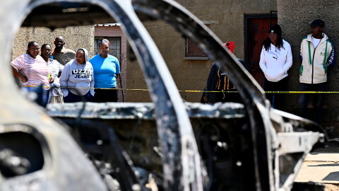 Community members stand at scene of a mass shooting on Saturday night when suspects opened fire at a bar in Wedela township, southwest of Johannesburg, South Africa, Sunday, Sept. 27, 2026.