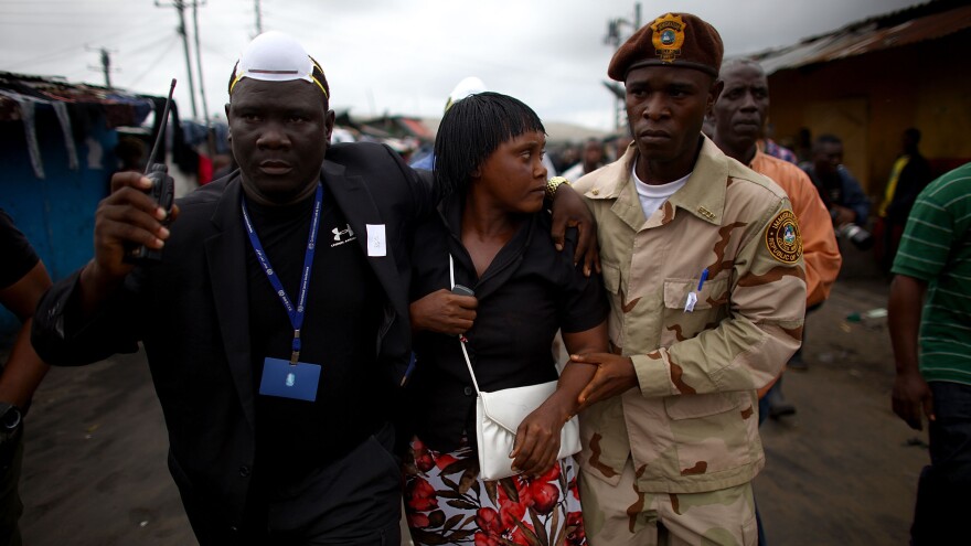 Government officials escort the commissioner of West Point, Haja Miatta Flowers, out of the neighborhood. She had returned to bring out her children, sparking Wednesday morning's riot in the Monrovia slum.