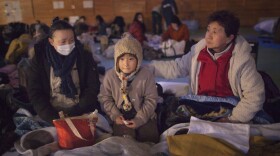 Yukie Ito, (L) tries to comfort her daughter Hana,8, (C) with grandmother Tamiyo (R) at a cold refugee center for the homeless March 16, 2011 in Kesennuma, Miyagi province, Japan. 